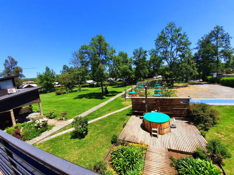 Parque del apart hotel en Pucón con las tinajas sobre decks de madera