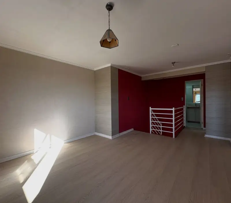 Sala de estar junto a la escalera interior del departamento en el centro de Temuco