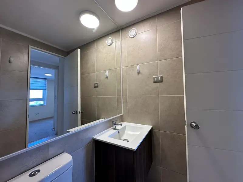 Baño con lavamanos, mueble y espejo del departamento en Plaza Parque Los Poetas, Temuco
