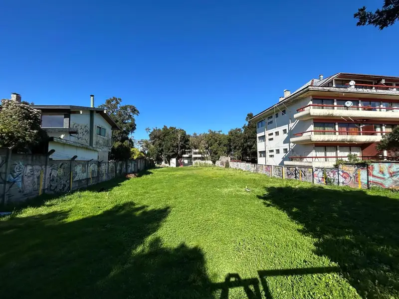 Terreno de 1.000 m² en Pucón visto desde el frente, con edificios a ambos lados