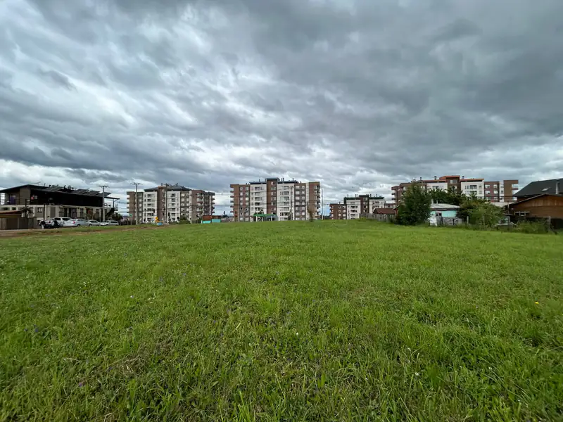 Vista general del terreno en venta en Av. Luis Durand, Temuco, con los edificios del sector al fondo