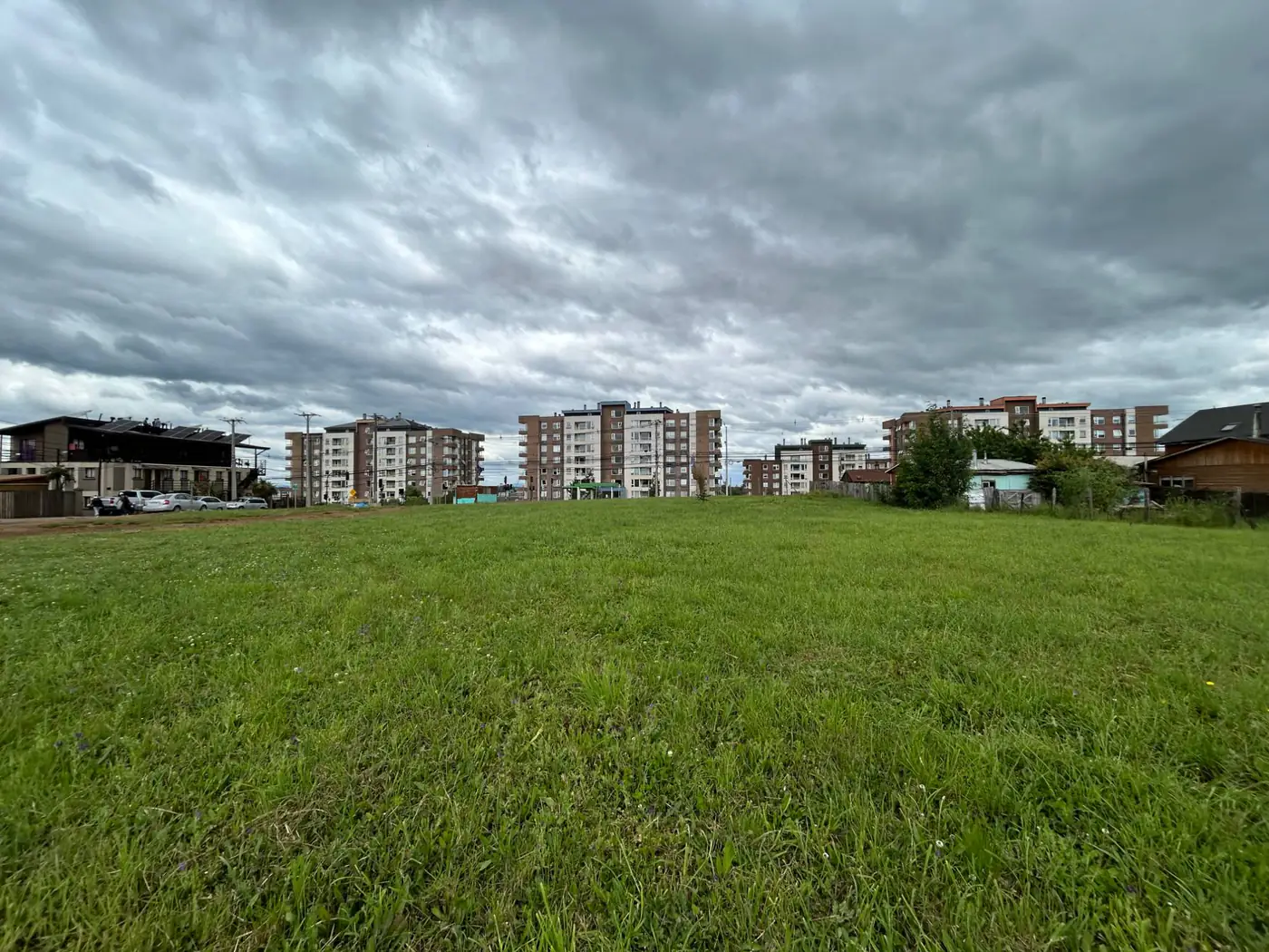 Vista general del terreno en venta en Av. Luis Durand, Temuco, con los edificios del sector al fondo